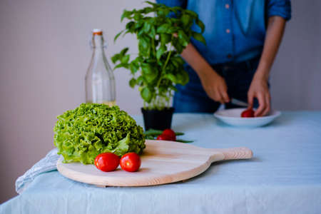 young woman wearing jeans cooking healthy vegetarian detox food. Ingredients and preparation for healthy Italian foodの写真素材