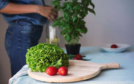 young woman wearing jeans cooking healthy vegetarian detox food. Ingredients and preparation for healthy Italian foodの写真素材