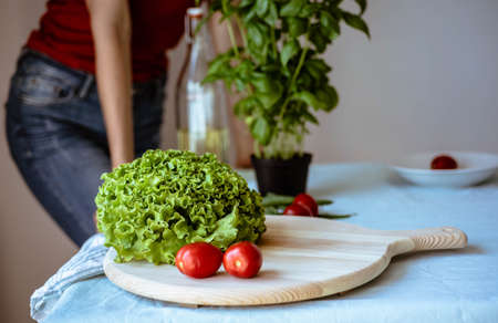 young woman wearing jeans cooking healthy vegetarian detox food. Ingredients and preparation for healthy Italian foodの写真素材