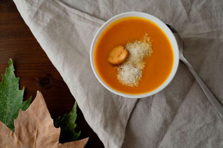 Flat-lay of fall warming pumpkin cream soup with croutons over tablecloth background Autumn vegetarian, vegan, healthy comfort food eating conceptの写真素材