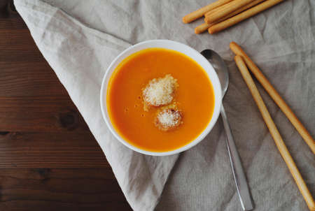 Flat-lay of fall warming pumpkin cream soup with croutons over tablecloth background Autumn vegetarian, vegan, healthy comfort food eating conceptの写真素材