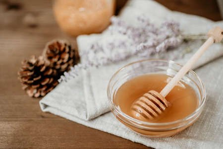 Honey in glass bowl with wooden spoon and Russian sage over wooden background.の写真素材