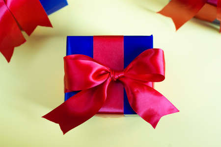flat-lay of present box with red bow ribbon on pastel yellow background. Christmas new year or birthday gift boxの写真素材