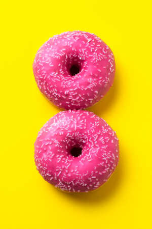View from above with two glazed donuts over yellow background. Background for woman day, 8 March. 8 March and Women's Day concept.の写真素材
