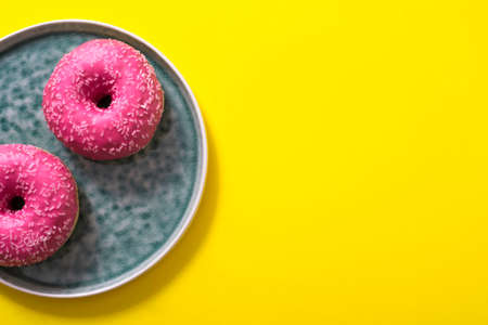 yellow background with pink donuts and copy space. Flat lay of sweetsの写真素材