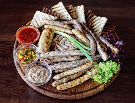 A bunch of meaty sausages and toasted bread with sauce on a rustic wooden cutting board.の写真素材