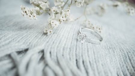 Close up of elegant diamond ring with white flower and gray scarf background. Wedding ring.の写真素材