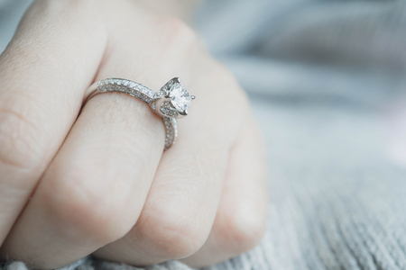 Close up of elegant diamond ring with feather and gray Scarf background. Diamond ring.の写真素材