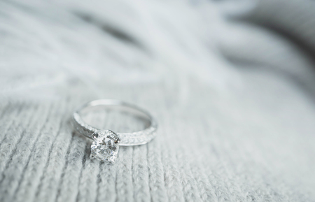Close up of elegant diamond ring with feather and gray Scarf background. Diamond ring.の写真素材