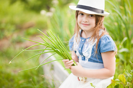 Little girl with onion in domestic gardenの写真素材