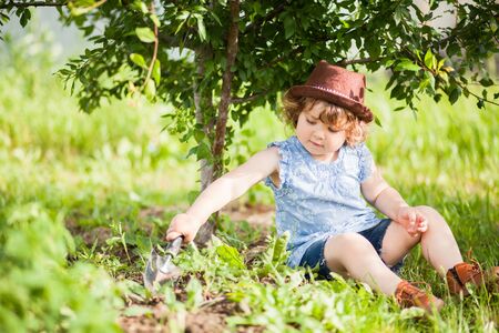 Cute little gardener sitting under the threeの写真素材