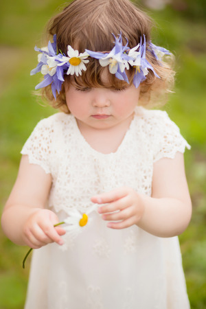 vertical natural light photo of a little girl guessing on a flower in ? sunny sammer dayの写真素材