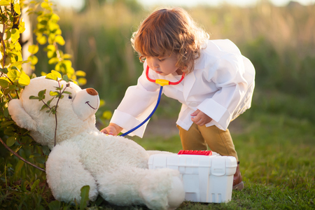 Adorable little girl role playing. little doctor. active play outdoors, beautiful sunset lightの写真素材