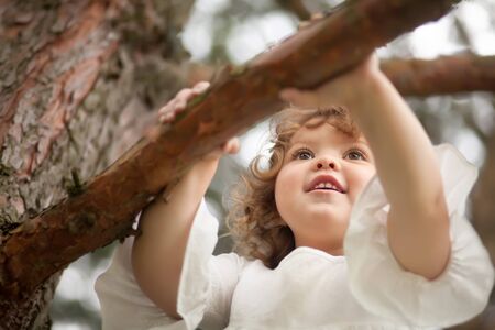 Adorable toddler girl climb a three, closeup photoの写真素材