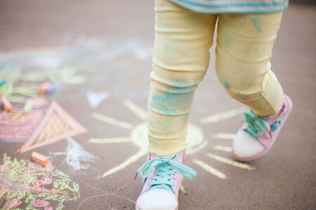 Little cute fun girl enjoy summer days in the park. closeup photo hapiness and childhood concept. chalk drawing on the asphaltの写真素材