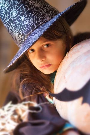 Cute little girl wearing halloween costume. Little witch with giant pumpkin