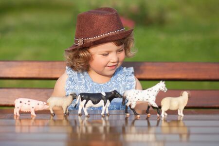 Cute toddler girl playing with farm animal figures outdoorsの写真素材
