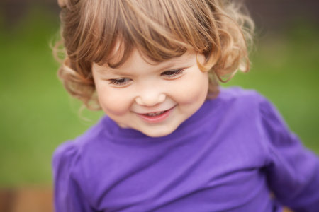 smiling  curl hair blondtoddler girl, closeup portrait.