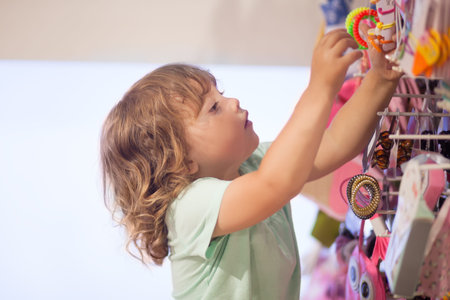Adorable toddler girl in baby apparel store, buying bijouterieの写真素材