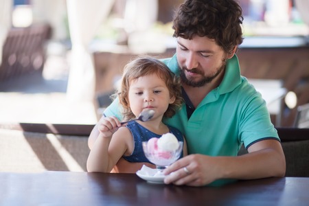 Father feeding llittle girl with ice cream, indoors. Family lifestyleの写真素材