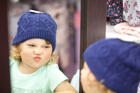Adorable toddler girl in baby apparel store, buying clothesの写真素材