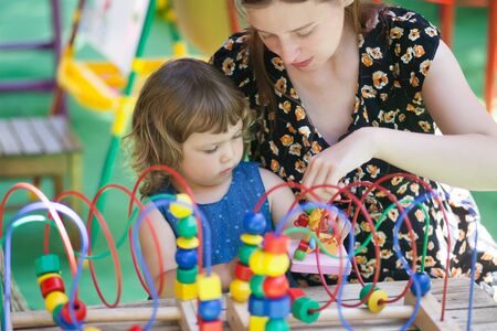 little girl and mother playing with educational toy - labyrinth. kindergarten concept, lifestyle. Early education and development. child and adult playing together.の写真素材