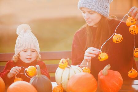 Happy family preparing for Halloween, choosing pumpkins outdoors. Fall day, warm toned photoの写真素材