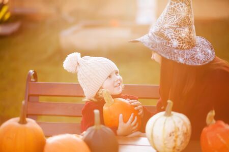 Happy family preparing for Halloween, choosing pumpkins outdoors. Fall day, warm toned photoの写真素材