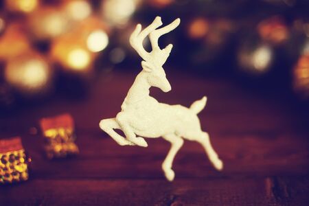Christmas festive background with beautiful deer, golden balls and pine cons on wooden deck table, toned photo.の写真素材