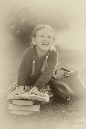 Old-fashioned little girl wearing school uniform. Smiling, holding pile of schoolbooks, laughing,...