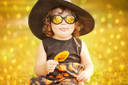 Little stylish witch outdoors, wearing halloween costume, ready for trick-or-treat, beautiful lightings, pop art.の写真素材