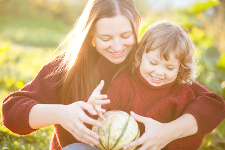 Happy family mom and child outdoors with little pumpkin, copyspace.の写真素材