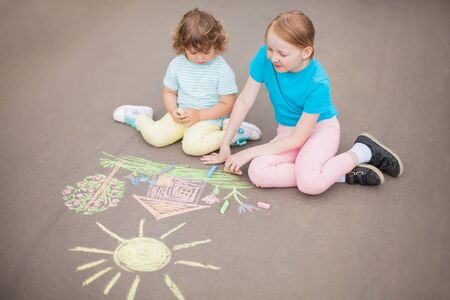Little girls sisters chalking at the asphaltの写真素材
