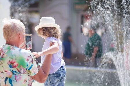 grandmother and her granddaughter walking in the city, making selfie, taking time together. An elderly woman and a child, grandma's love and care.の写真素材