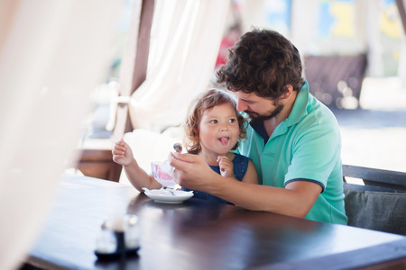 Father feeding llittle girl with ice cream, indoors. Family lifestyleの写真素材