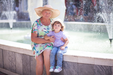 grandmother and her granddaughter walking in the city, taking time together. An elderly woman and a...