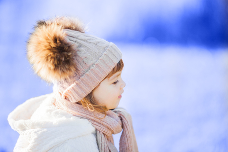 Cute toddler girl outdoors on a sunny winter day, walking, snowy dayの写真素材