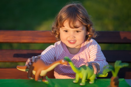 toddler kid, little girl having fun playing with a toy dinosaur, horizontal natural light photo,の写真素材