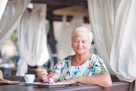 An eldery woman sitting in the open air cafe, relaxing aloneの写真素材