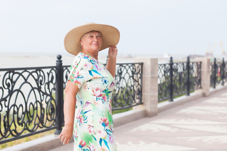 An elderly woman traveler posing, sea on a backgroundの写真素材