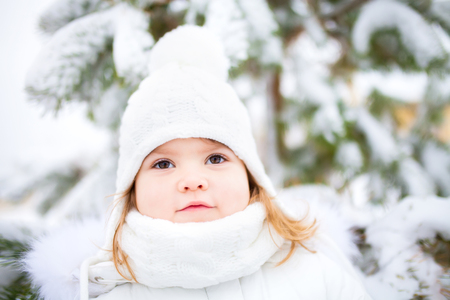 A cute toddler girl outdoors on a sunny winter day, walking on a snowy day.の写真素材