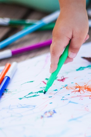 Adorable little girl drawing with felt-tip pens outdoors, closeup. Summer leisure. Talantes kids, early art education.の写真素材