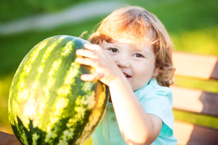 Sunny summer day, adorable little girl eats water melon, picnic outdoors, healthy food.の写真素材