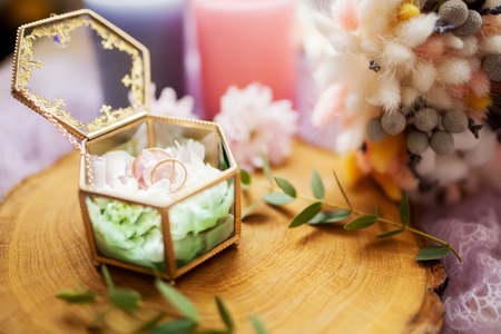 Wedding rings in beautiful glass jewelry box on a wooden texture surface, rustic stule, minimalism. Flat lay, top viewの写真素材