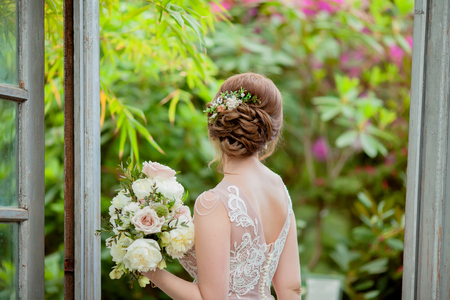 Bride in the greenhouse with tropical plants, wearing beautiful vintage dress, holding wedding bouquet. close up, copy spaceの写真素材