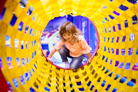 Cute happy toddler girl playing on a playground or kindergarten