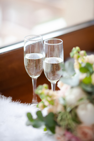 Wedding morning, two glasses of champagne and bride's bouquet of peony and roses, lots of greenery.の写真素材