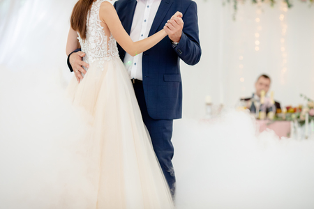 Father and daughter dance at the wedding. Dancing in the fog. Groom at the background, watching themの写真素材