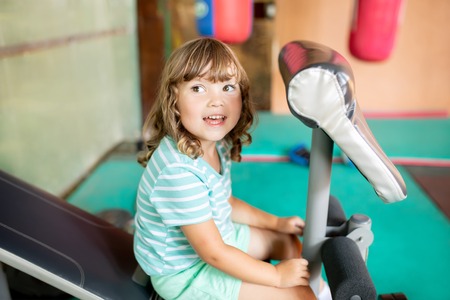 Adorable little kid girl making exercises on sports training apparatus at the gym, healty sportive child.の写真素材