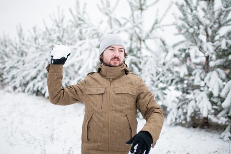 Attractive young man playing snowballs, winter day, family activity.の写真素材